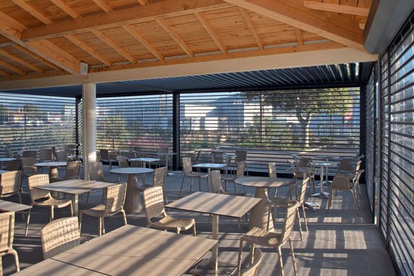 Rideaux DéclicVision transparents autour d’une terrasse couverte avec tables et chaises