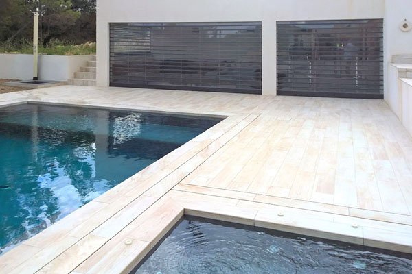 Deux rideaux DéclicVision gris transparents devant des ouvertures au bord d’une piscine