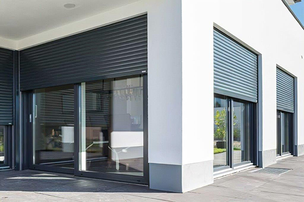 Volets Thermobox gris sur de grandes baies vitrées d’un bâtiment blanc
