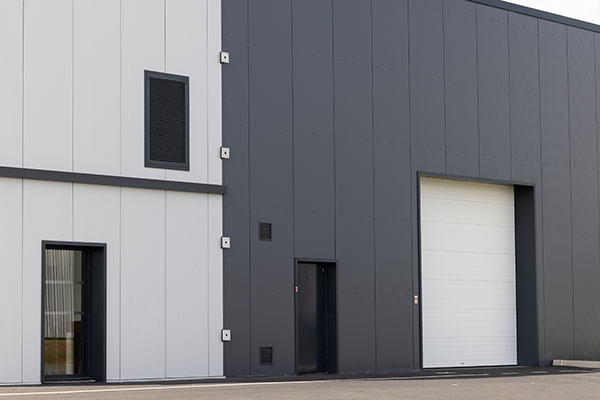 Porte sectionnelle industrielle à panneaux sur un bâtiment d’activité