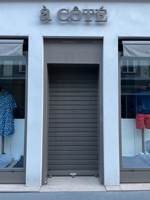 Rideau métallique gris fermant l'entrée d'une boutique